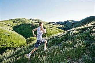 Caucasian athlete running on rural hills