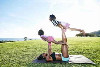 Mother holding children on yoga mat in park