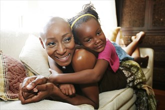 Black mother and daughter laying on sofa