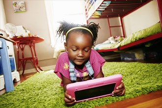 Black girl using digital tablet in bedroom