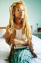 Black woman with dreadlocks sitting on bed
