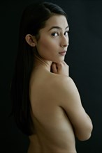 Nude Hispanic woman looking over shoulder