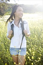 Mixed race woman carrying backpack in field