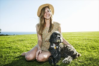 Caucasian woman sitting in field with dog