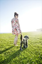 Caucasian woman walking dog in field