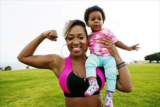 Black woman holding daughter in field