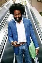 Mixed race businessman using cell phone on escalator