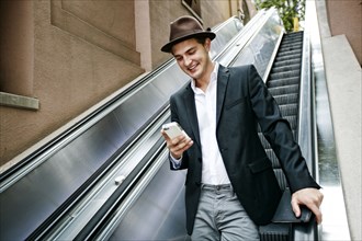 Caucasian businessman using cell phone on escalator