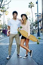 Caucasian couple carrying skateboards