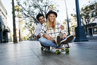 Caucasian couple riding skateboard