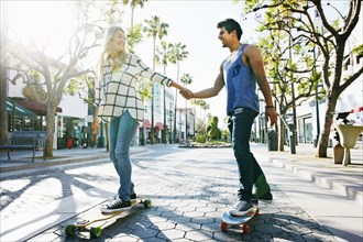 Caucasian couple riding skateboards