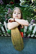 Caucasian girl holding skateboard on sidewalk