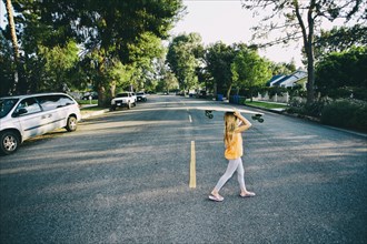 Caucasian girl crossing suburban street