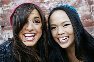Women laughing in front of brick wall