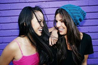 Women laughing near purple brick wall