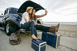Women with luggage and vintage car on beach
