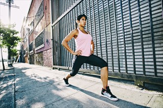 Mixed race woman stretching on sidewalk