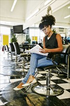 Mixed race hairstylist reading in salon