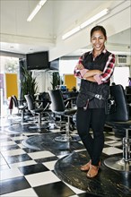 Hispanic hairstylist smiling in salon