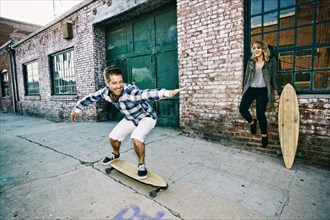 Caucasian couple skateboarding on sidewalk