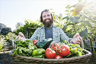Caucasian man holding basket of vegetables in garden