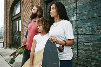 Family holding skateboards outdoors