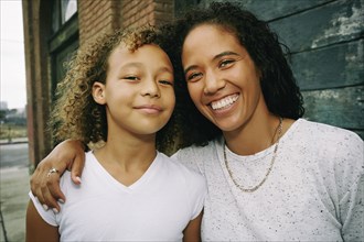 Mixed race mother and daughter hugging outdoors