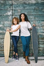 Mixed race mother and daughter holding skateboards