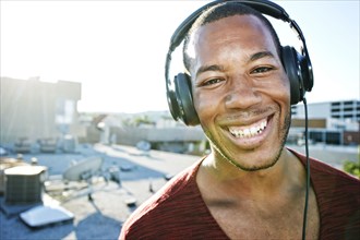 African American man listening to headphones on urban rooftop