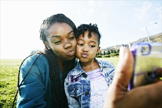 Black mother and daughter taking selfie outdoors