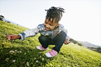 Black girl picking flowers in field