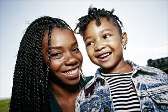 Black mother and daughter smiling outdoors
