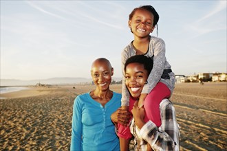 Three generations of Black women smiling on beach