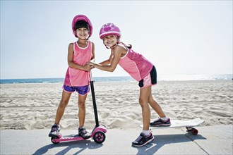 Girls playing on skateboard at scooter at beach
