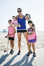 Mother and daughters holding kettle bells at beach