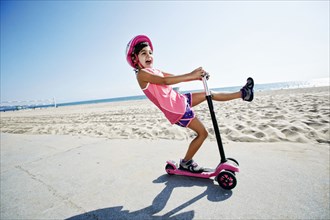 Girl riding scooter at beach