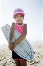Mixed race girl holding skateboard at beach