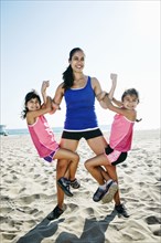 Strong mother lifting daughters at beach