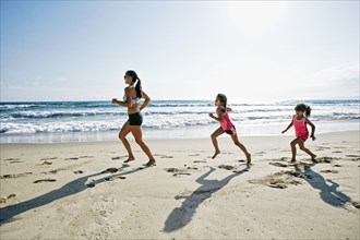 Mother and daughters running at beach