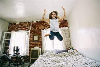 Native American girl jumping on bed
