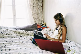 Native American girl recording music on bed
