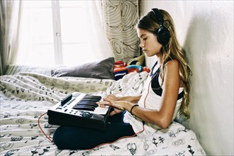 Native American girl playing keyboard on bed
