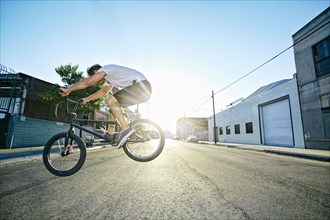 Caucasian man jumping on BMX bike on street