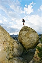 Mixed race woman climbing rock formation