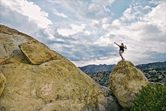 Mixed race woman climbing rock formation