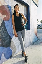 Mixed race athlete leaning on mural wall
