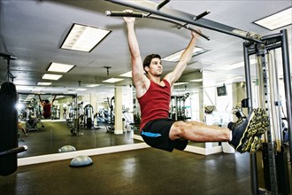 Man doing pull-ups in gymnasium