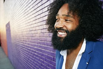 Mixed race man smiling outdoors near purple wall