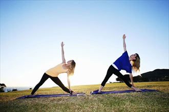 Caucasian women practicing yoga in field