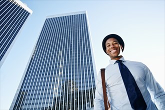 Black businessman smiling under highrise buildings